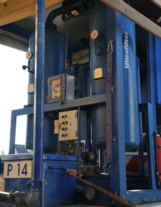Zwei große blaue Druckbehälter mit angeschlossenen Leitungen und Ventilen in einem Technikcontainer.